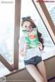 A woman sitting on a window sill holding a bag of chips.