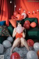 A woman sitting on a couch holding a bunch of balloons.