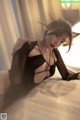 A woman in a black dress laying on a bed.