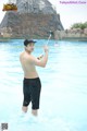 A shirtless man taking a selfie in a water park.