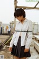 A woman in a white shirt and plaid skirt standing on a roof.