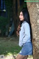 A woman leaning against a tree in a park.