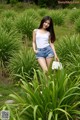 A woman in a white tank top and denim shorts posing for a picture.