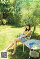 A woman sitting on a white chair in a yard.