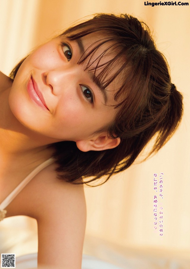 A woman in a white tank top posing for a picture.