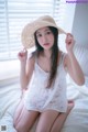 A woman sitting on a bed wearing a straw hat.