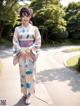 A woman in a kimono standing on a sidewalk.