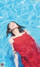 A woman in a red dress floating in a pool.