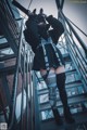 A woman in a black jacket and black boots standing on a set of stairs.