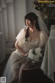 A woman in a wedding dress sitting on a chair.