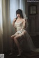 A woman in a wedding dress sitting on a chair.