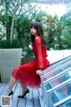 A woman in a red dress sitting on a wooden deck.