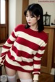 A woman in a red and white striped sweater and white stockings.