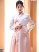 A woman in a pink and white hanbok poses for a picture.