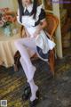 A woman in a maid outfit sitting on a chair.